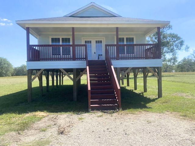 raised beach house with french doors, a front lawn, and a porch