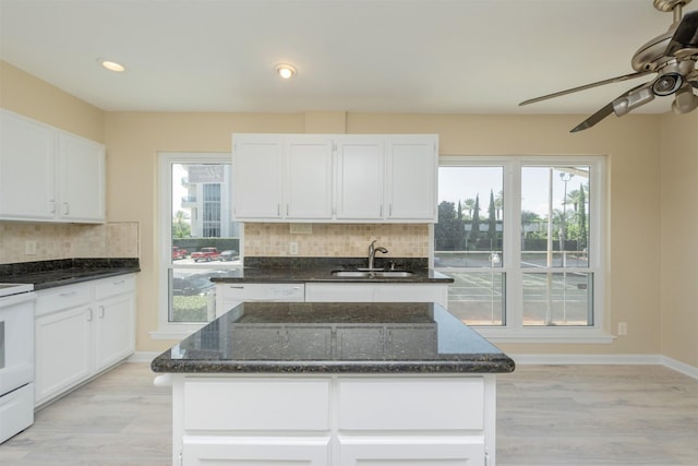 kitchen featuring white cabinetry, dark stone countertops, and sink