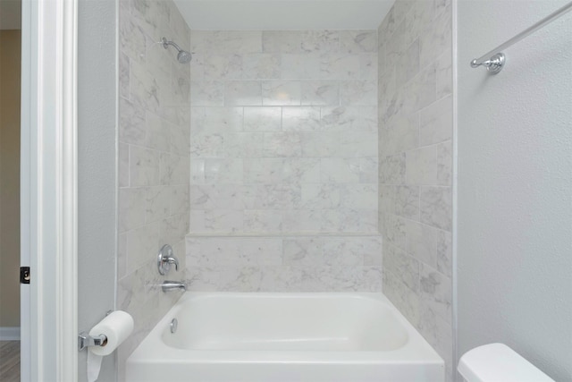 bathroom featuring toilet and tiled shower / bath