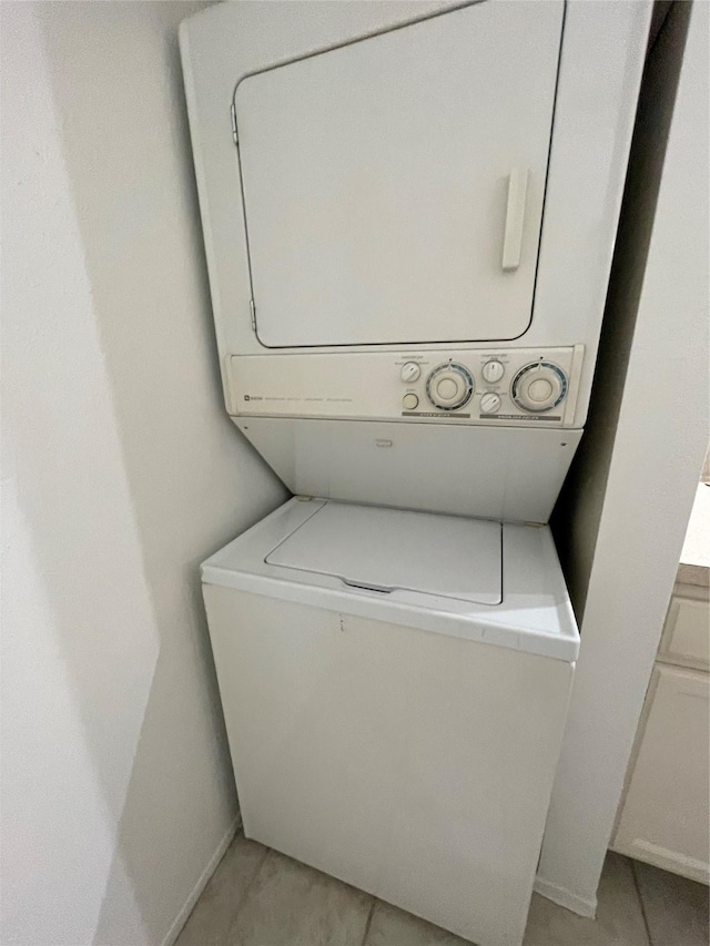 clothes washing area with stacked washer and dryer and light tile patterned flooring