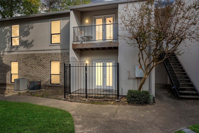 rear view of house featuring cooling unit, a balcony, and french doors