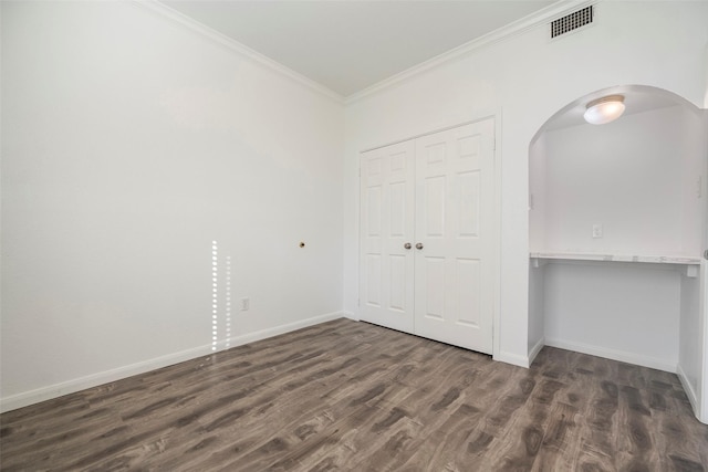 unfurnished bedroom featuring dark hardwood / wood-style floors, ornamental molding, and a closet