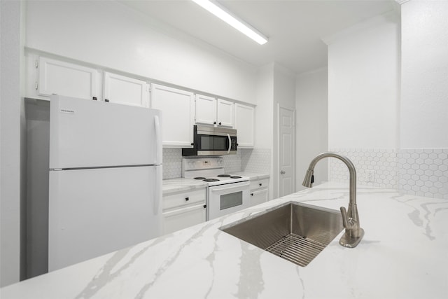 kitchen with decorative backsplash, light stone counters, white appliances, sink, and white cabinetry