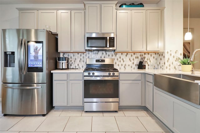 kitchen with decorative backsplash, decorative light fixtures, stainless steel appliances, and light tile patterned flooring