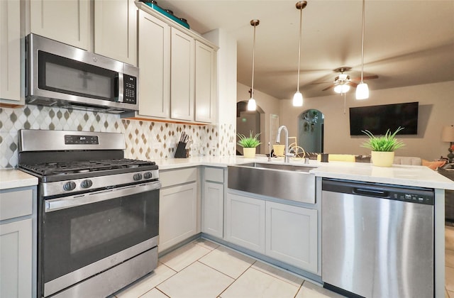 kitchen featuring kitchen peninsula, appliances with stainless steel finishes, tasteful backsplash, sink, and pendant lighting