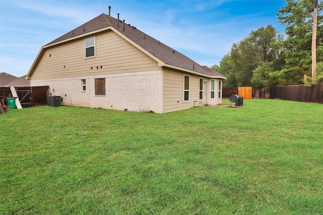 rear view of house featuring a yard and central air condition unit