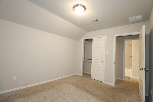 unfurnished bedroom with light carpet, a closet, and lofted ceiling