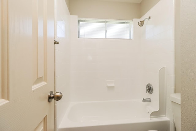 bathroom featuring tiled shower / bath combo and toilet