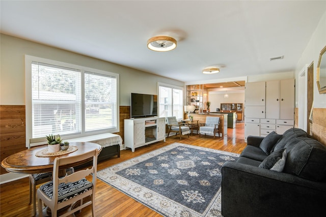 living room with hardwood / wood-style floors, plenty of natural light, and wood walls