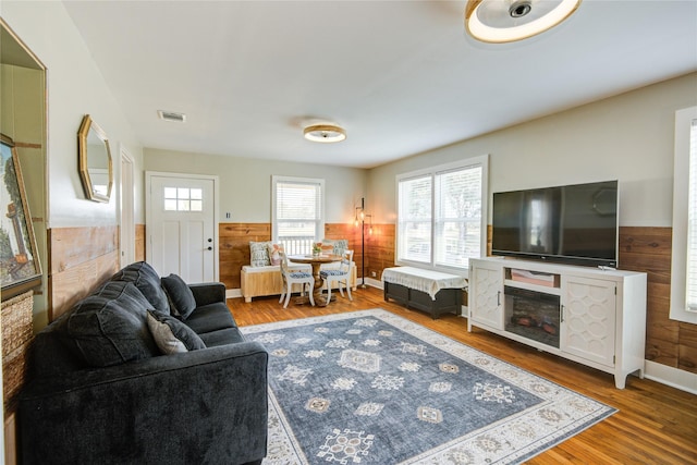 living room with hardwood / wood-style flooring and wood walls