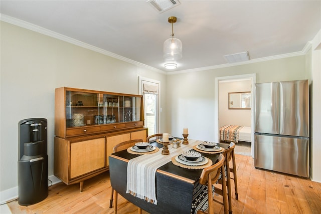 dining room featuring light wood-type flooring and crown molding