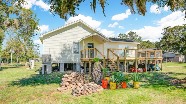 rear view of property featuring a lawn and a deck