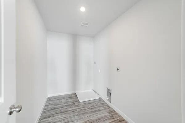 clothes washing area featuring hardwood / wood-style flooring and electric dryer hookup