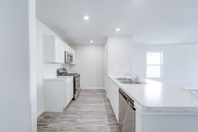 kitchen featuring kitchen peninsula, stainless steel appliances, sink, light hardwood / wood-style flooring, and white cabinets