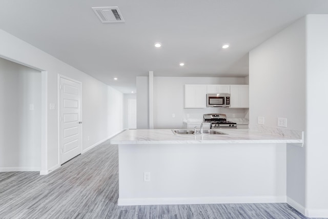 kitchen with kitchen peninsula, stainless steel appliances, sink, light hardwood / wood-style flooring, and white cabinets