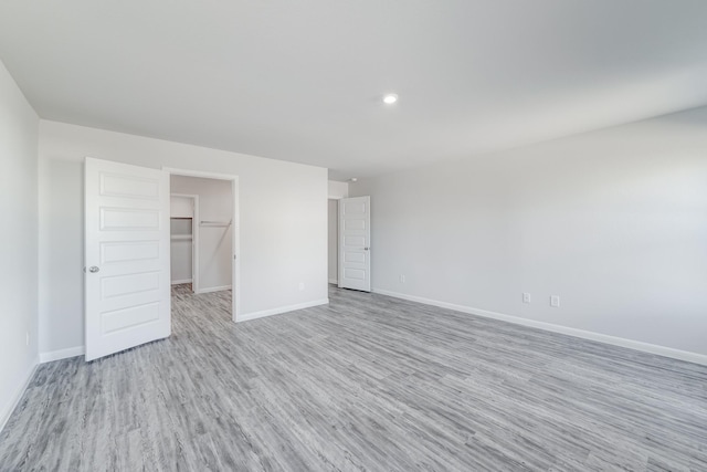 unfurnished bedroom with light wood-type flooring, a walk in closet, and a closet