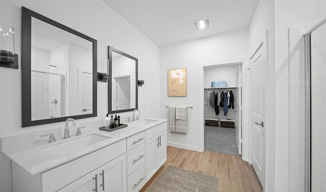 bathroom featuring wood-type flooring, a shower with door, and vanity