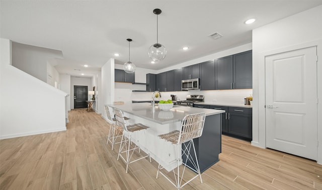 kitchen with stainless steel appliances, hanging light fixtures, light countertops, and a kitchen breakfast bar