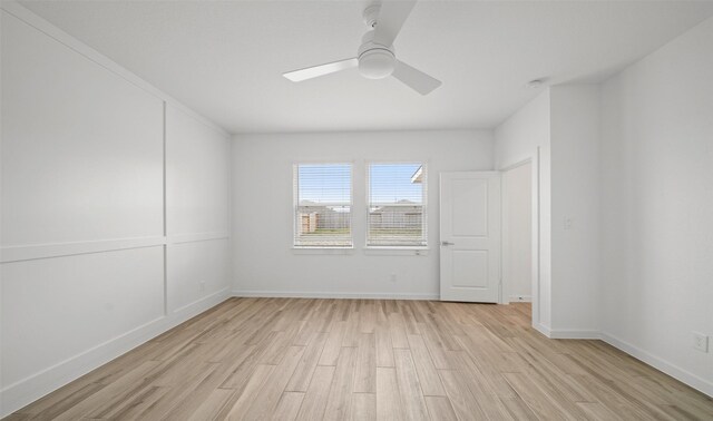 empty room featuring light wood finished floors, baseboards, and a ceiling fan