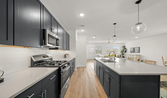 kitchen with a breakfast bar, pendant lighting, stainless steel appliances, light countertops, and a sink