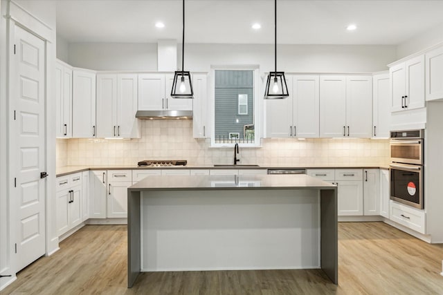 kitchen with light wood-type flooring, a center island, white cabinetry, and hanging light fixtures