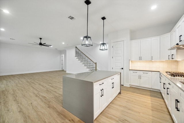 kitchen with ceiling fan, light hardwood / wood-style flooring, backsplash, decorative light fixtures, and white cabinets