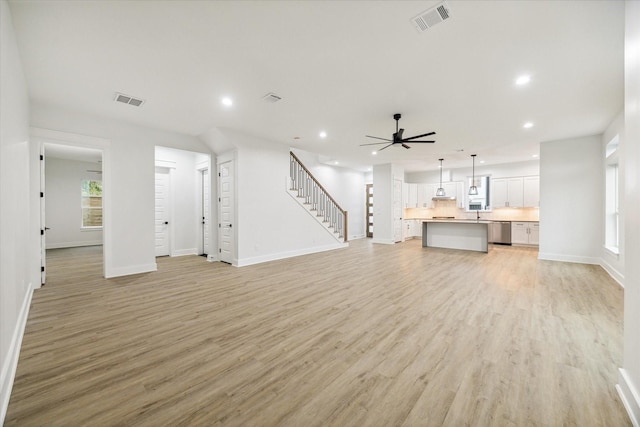 unfurnished living room with ceiling fan and light wood-type flooring