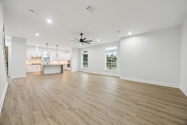 unfurnished living room with ceiling fan and light hardwood / wood-style flooring