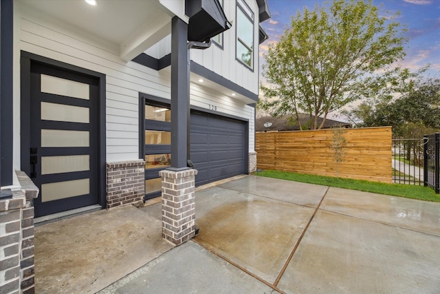 patio terrace at dusk featuring a garage