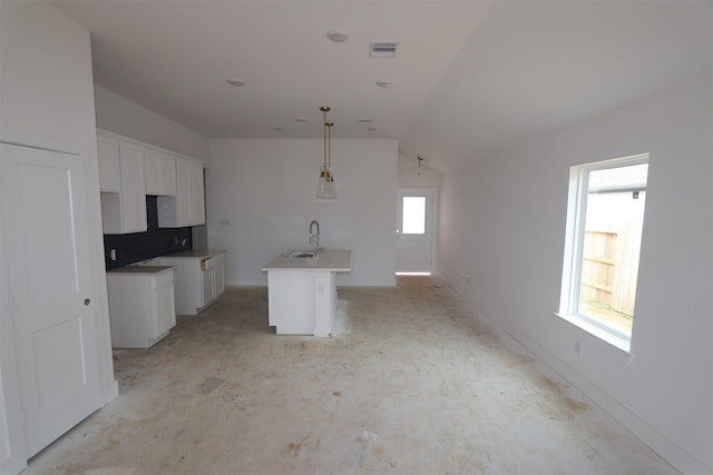 kitchen featuring a sink, white cabinets, hanging light fixtures, light countertops, and an island with sink