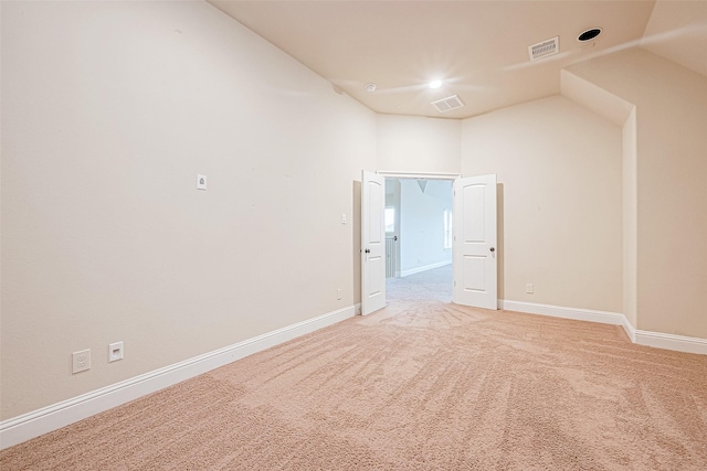 carpeted spare room featuring vaulted ceiling