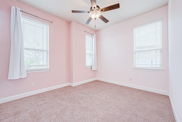 carpeted spare room with a wealth of natural light and ceiling fan