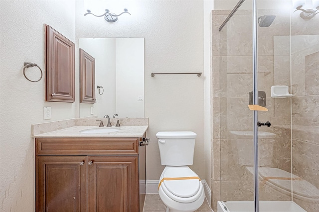 bathroom with tile patterned flooring, vanity, a shower with shower door, and toilet