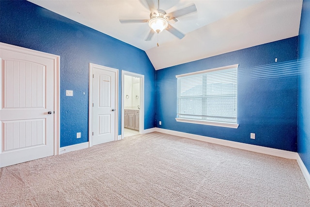 unfurnished bedroom with carpet flooring, ceiling fan, lofted ceiling, and ensuite bath