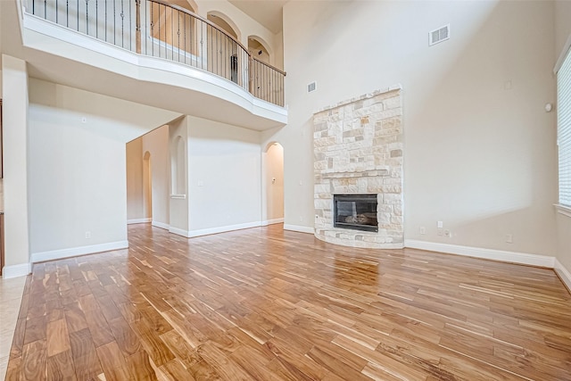 unfurnished living room with a fireplace, a high ceiling, and wood-type flooring