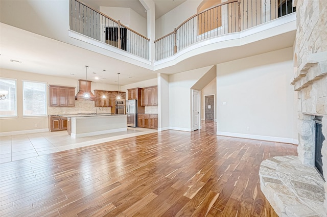 living room with a fireplace, a towering ceiling, light hardwood / wood-style floors, and sink