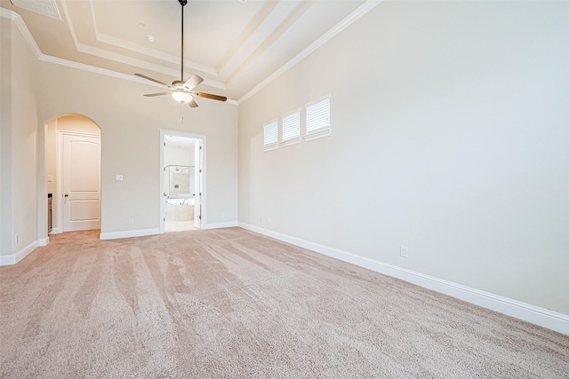 interior space with ensuite bath, ceiling fan, crown molding, light colored carpet, and a tray ceiling