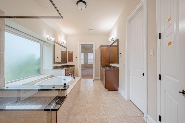 bathroom with tile patterned floors, vanity, and tiled bath