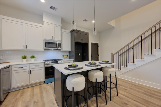 kitchen featuring a center island, stainless steel appliances, light hardwood / wood-style flooring, pendant lighting, and white cabinets