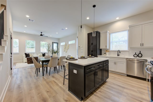 kitchen with pendant lighting, white cabinets, a center island, stainless steel appliances, and light wood-type flooring