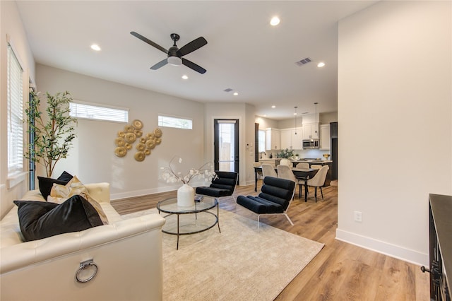 living room with ceiling fan and light hardwood / wood-style flooring