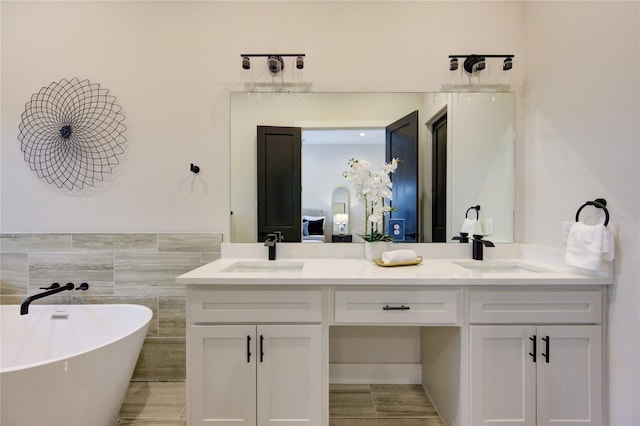 bathroom with tile patterned flooring, vanity, a bath, and tile walls