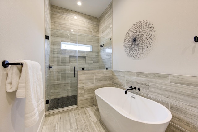 bathroom featuring tile walls and independent shower and bath