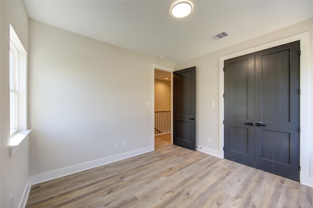 unfurnished bedroom with light wood-type flooring and a closet