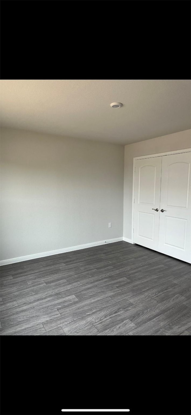 unfurnished bedroom featuring a closet and dark wood-type flooring