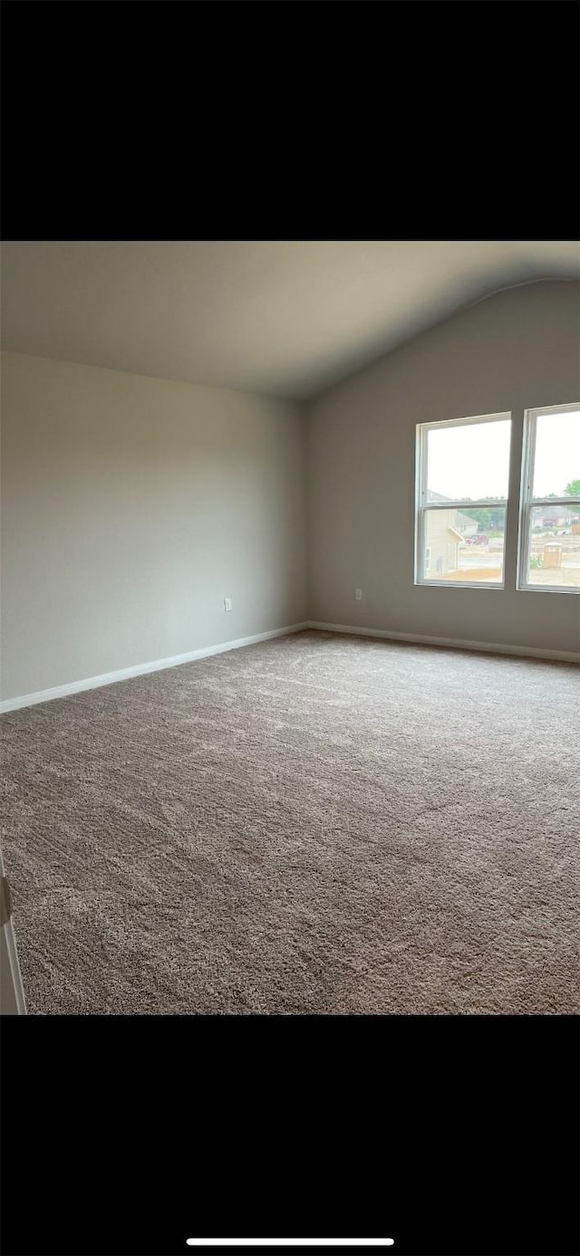 carpeted spare room featuring vaulted ceiling