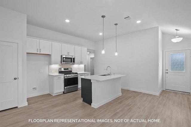 kitchen with appliances with stainless steel finishes, a center island with sink, white cabinetry, and pendant lighting