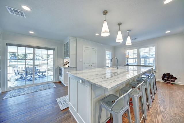 kitchen featuring a sink, white cabinetry, dark wood-style flooring, glass insert cabinets, and crown molding