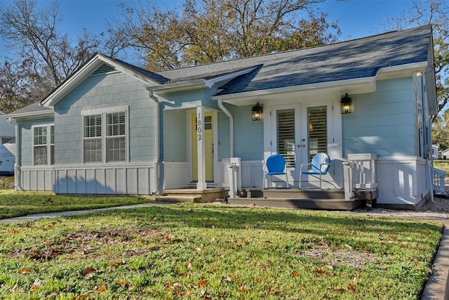 ranch-style house featuring french doors, covered porch, and a front yard