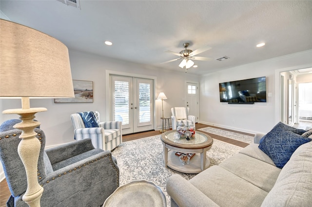 living room with ceiling fan, wood-type flooring, crown molding, and french doors